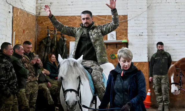 A Ukrainian serviceman rides a horse during a hippotherapy session in Kyiv on March 17, 2023. In a cosy barn on the outskirts of Kyiv, a group of Ukrainian soldiers are taking a break from battle with a session of hippotherapy – using riding and contact with horses to achieve a therapeutic effect. (Photo by Sergei Supinsky/AFP Photo)