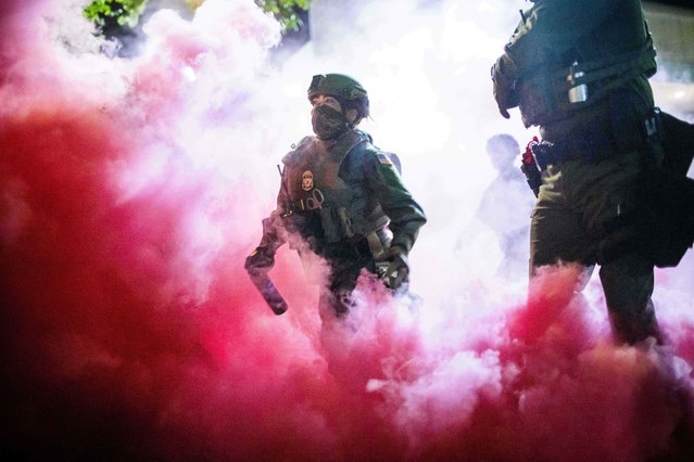 Police and federal officers throw gas canisters to disperse protesters near a U.S. Immigration and Customs Enforcement facility in Portland, Ore. on Sunday, October 5, 2025. (Photo by Ethan Swope/AP Photo)