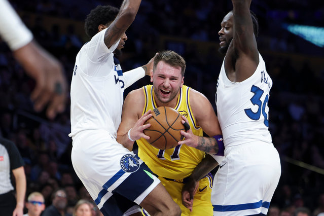 Los Angeles Lakers guard Luka Doncic, center, drives against Minnesota Timberwolves forward Jaden McDaniels, left, and forward Julius Randle during the first half of an NBA basketball game, Friday, October 24, 2025, in Los Angeles. (Photo by Jessie Alcheh/AP Photo)