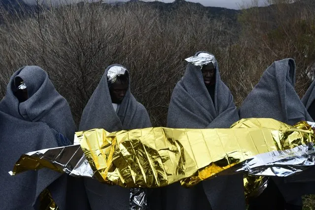 Migrants use blankets to warm themselves upon their arrival at the village of Skala Sikaminias, on the Greek island of Lesbos, after crossing the Aegean sea from Turkey, Saturday, February 29, 2020. Hundreds of refugees and migrants in Turkey have begun heading for the country's land and sea borders with Greece, buoyed by Turkish officials' statements indicating they will not be hindered from crossing the frontier to head into Europe. (Photo by Michael Varaklas/AP Photo)