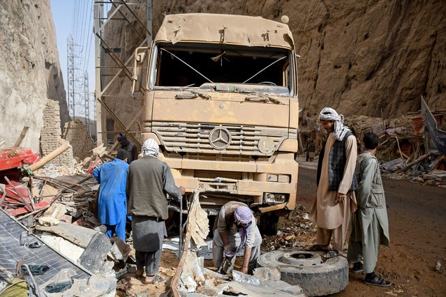Afghan men check a damaged truck along a highway, following an earthquake at the Tang-e Tashkurgan in the Khulm district of Samangan province on November 3, 2025. (Photo by Atif Aryan/AFP Photo)