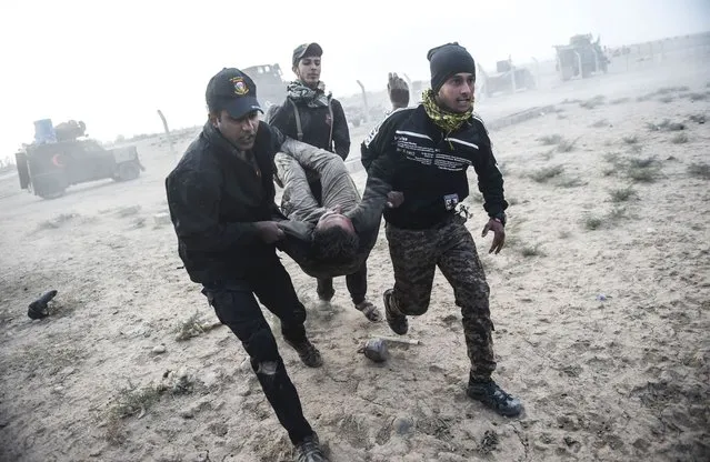 Iraqi Counter Terrorism Section (CTS) members carry an injured comrade during clashes with Islamic State (IS) group jihadists near the village of Bazwaya, on the eastern edges of Mosul, on October 31, 2016. Iraqi special forces neared the eastern city limits of Mosul on Monday, tightening the noose as the offensive to retake the Islamic State group stronghold entered its third week. (Photo by Bulent Kilic/AFP Photo)