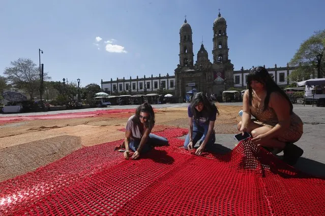 Members of the Colectivo Hilos set up the work of art made from red fabric, titled “Blood of My Blood”, made to bring attention to the femicides that have occurred in the country, prior to the mobilization for International Women's Day that will be held tomorrow, in the main square of Zapopan, Jalisco state, Mexico, 07 March 2022. (Photo by Francisco Guasco/EPA/EFE)
