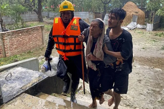 Rescue workers help an elderly woman to reach a makeshift shelter after a storm in Teknaf, near Cox's Bazar, Bangladesh, Sunday, May 14, 2023. (Photo by Al-emrun Garjon/AP Photo)