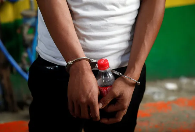 A man who was detained because of a pending criminal court case, is pictured holding a soda bottle while handcuffed, during an anti-drugs operation in Mandaluyong, Metro Manila in the Philippines, November 10, 2016. (Photo by Erik De Castro/Reuters)