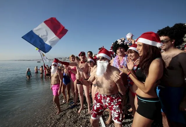 A swimmer waves a French flag as he takes part in the traditional Christmas bath during an unusually warm winter day in Nice, southeastern France, December 20, 2015. (Photo by Eric Gaillard/Reuters)