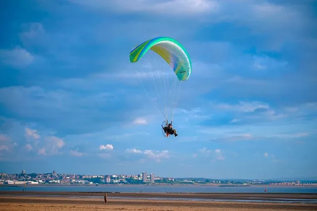 A man flying a paramotor over Crosby Beach, Merseyside, North West England on the eve of the Summer Solstice on Tuesday, June 20, 2023. (Photo by Peter Byrne/PA Images via Getty Images)