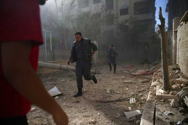 Civil Defence members run amidst debris after a strike on the rebel held besieged city of Douma, in the eastern Damascus suburb of Ghouta, Syria November 8, 2016. (Photo by Bassam Khabieh/Reuters)