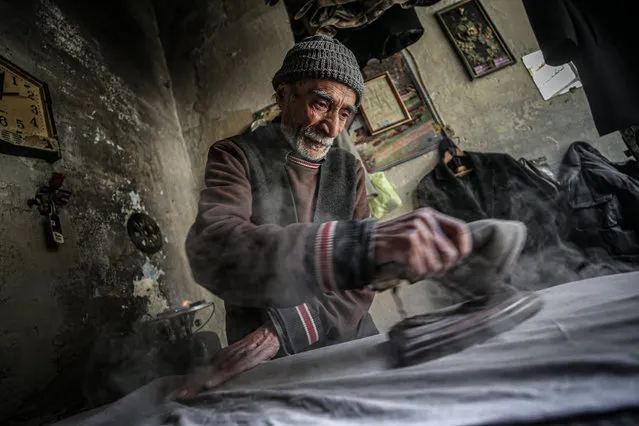 69 years old Syrian Abdo Dihnin, father of 5 children, earns his and his famliy's life with ironing for 50 years in Idlib, Syria on February 24, 2021. (Photo by Muhammed Said/Anadolu Agency via Getty Images)