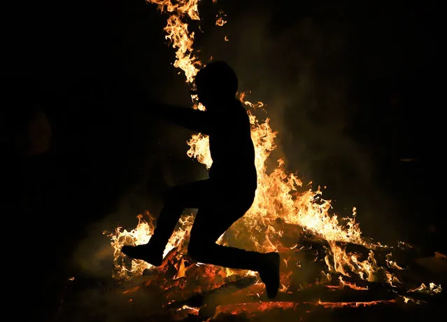 Silhouette of a person jumping over a bonfire as part of the Newroz celebrations, marking the arrival of spring in Baku, Azerbaijan on March 02, 2021. The “fire Wednesday”, considered as one of the symbols of Newroz celebrations, began in Azerbaijan. Despite the restrictions due to the new type of coronavirus (Covid-19) pandemic, Azerbaijanis gathered around the bonfires they set up in the neighborhoods for the “fire Wednesday”, which is the second of the “four wednesdays” in their old traditions and has similar characteristics to the spring arrival belief in Anatolia. (Photo by Resul Rehimov/Anadolu Agency via Getty Images)