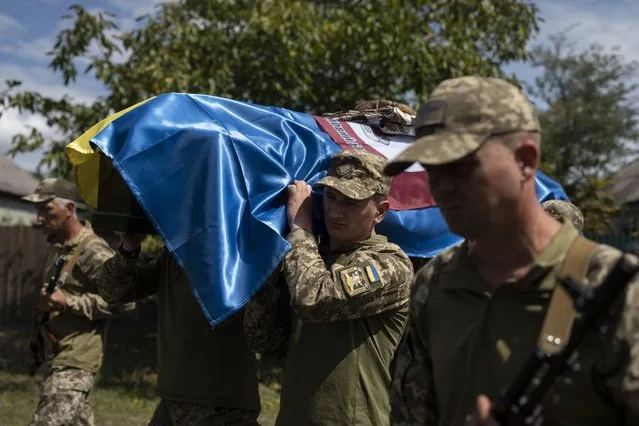Soldiers carry the coffin with 22-year old Oleksander Mykhailenko's remains in Zhukin, Ukraine, Friday, August 11, 2023. Oleksander, a soldier in the Ukrainian army, died in battle in the Kharkiv region in March this year but his body was only identified recently. (Photo by Bram Janssen/AP Photo)