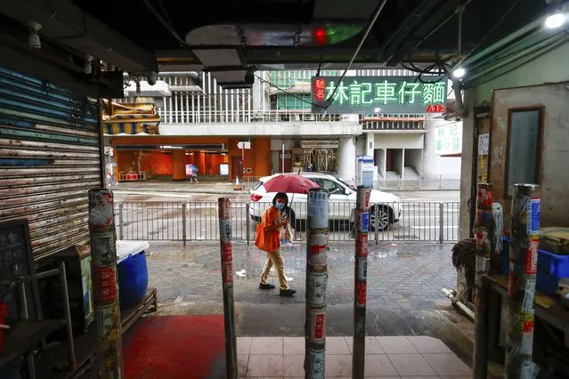 A woman holding an umbrella walks past a shuttered store at a food centre as super typhoon Saola approaches Hong Kong on Friday, September 1, 2023. (Phoot by Daniel Ceng/AP Photo)