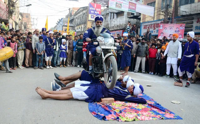 A Sikh man rides a motorbike over men lying in the road during a display marking the birthday of Guru Gobind Singh in Allahabad, India on January 14, 2016. (Photo by Prabhat Kumar Verma/ZUMA Press/Corbis)