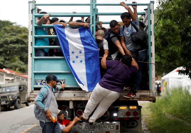 A Honduran migrant, part of a caravan trying to reach the U.S., climbs on a truck in Quezaltepeque, Guatemala on October 16, 2018. The group of some 2,000 Honduran migrants hit the road in Guatemala again Wednesday, hoping to reach the United States despite President Donald Trump's threat to cut off aid to Central American countries that don't stop them. (Photo by Edgard Garrido/Reuters)