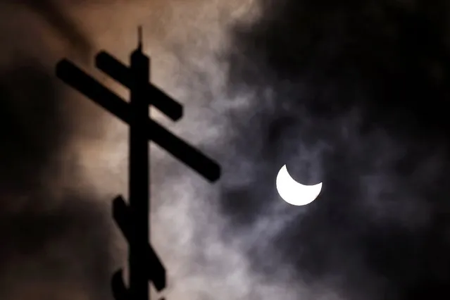 A partial solar eclipse forms in the sky through clouds near the cross of the Church of St Nicholas the Miracle-Maker in Sofia March 20, 2015. A partial eclipse was visible on Friday, the first day of northern spring, across parts of Africa, Europe and Asia. The total eclipse of the sun was only be visable in the Faroe Islands and the Norwegian archipelago of Svalbard in the Arctic Ocean. (Photo by Stoyan Nenov/Reuters)