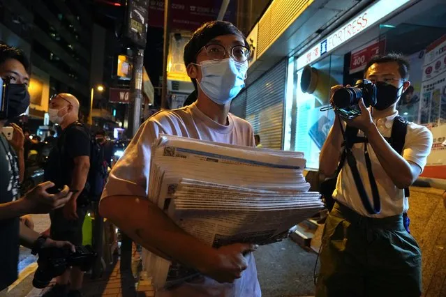 A man holds a stack of last issue of Apple Daily after purchase at a newspaper booth in Hong Kong, early Thursday, June 24, 2021. Hong Kong's pro-democracy Apple Daily newspaper will stop publishing Thursday, following last week's arrest of five editors and executives and the freezing of $2.3 million in assets under the city's year-old national security law. (Photo by Vincent Yu/AP Photo)