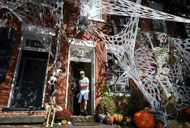 A mail carrier is framed by Halloween decorations along Prince Street on Friday October 13, 2023 in Alexandria, VA. (Photo by Matt McClain/The Washington Post)