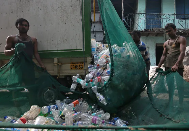 Men unload used plastic bottles from a mini-truck outside a recycling factory in Mumbai, November 20, 2018. (Photo by Francis Mascarenhas/Reuters)