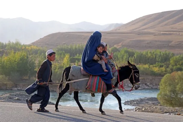 An Afghan burqa-clad woman with children ride a donkey in Kishim district of Badakhshan province on October 12, 2023. (Photo by Omer Abrar/AFP Photo)