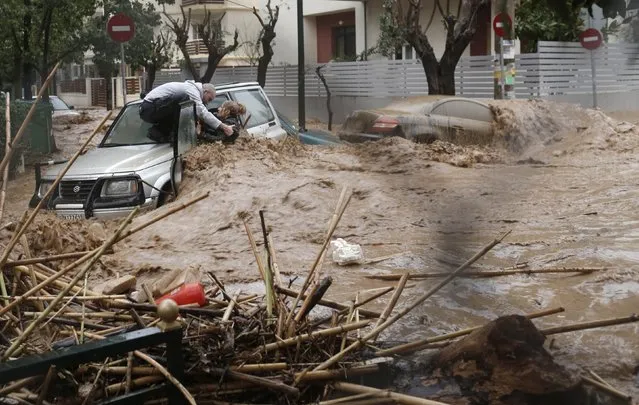 A woman is rescued from flood waters by a resident standing on top of her car during heavy rain in Chalandri suburb north of Athens February 22, 2013. (Photo by John Kolesidis/Reuters)