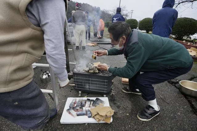 An evacuee volunteers to grill pieces of fish at a temporary evacuation center in Suzu in the Noto peninsula facing the Sea of Japan, northwest of Tokyo, Wednesday, January 3, 2024, following Monday's deadly earthquake. (Photo by Hiro Komae/AP Photo)