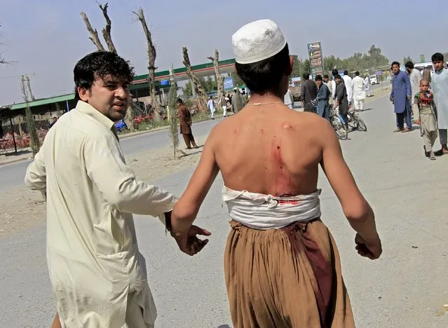 An Afghan man helps a wounded man at the site of a suicide attack that targeted a NATO convoy in Jalalabad city April 10, 2015. A suicide bomber in a car targeted a NATO convoy in Jalalabad in eastern Afghanistan on Friday killing at least five and wounding twelve civilians, provincial officials said. (Photo by Reuters/Parwiz)