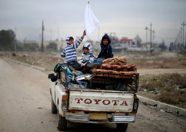A displaced Iraqi boy holds a white flag as his family flees during the battle between Iraqi rapid response forces and Islamic State militants at Tigris river frontline between east and west of Mosul , Iraq, January 25, 2017. (Photo by Ahmed Jadallah/Reuters)