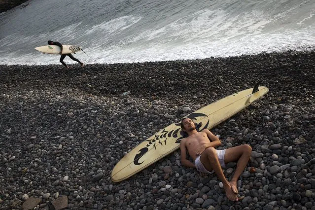Omar Diaz takes a nap after surfing in the Pacific Ocean on the coast of Lima, Peru, Wednesday, March 2, 2016. (Photo by Rodrigo Abd/AP Photo)