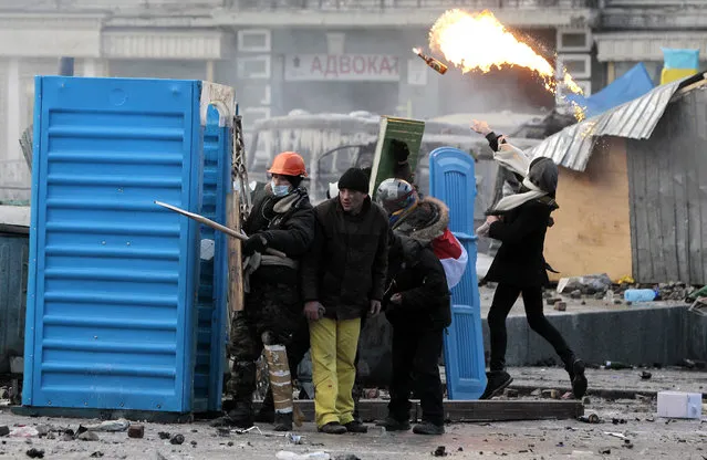 Protesters clash with police, in central Kiev, Ukraine, Monday, January 20, 2014. Protesters erected barricades from charred vehicles and other materials in central Kiev as the sound of stun grenades can be heard in the freezing air as police try to quell anti-government street protests. (Photo by Sergei Chuzavkov/AP Photo)