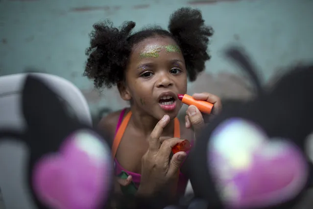A girl holds still for lipstick before the “Se Benze que da” block party, which was created by slain councilwoman Marielle Franco, in the Mare slum of Rio de Janeiro, Brazil, Saturday, February 23, 2019. (Photo by Silvia Izquierdo/AP Photo)