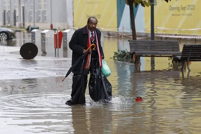 A man walks through a flooded street after heavy rains and bad weather in Lisbon, Portugal on December 13, 2022. The national civil protection appealed to citizens to restrict the maximum displacement due to bad weather in the districts of Lisbon and Setubal. (Photo by Antonio Pedro Santos/EPA/EFE/Rex Features/Shutterstock)