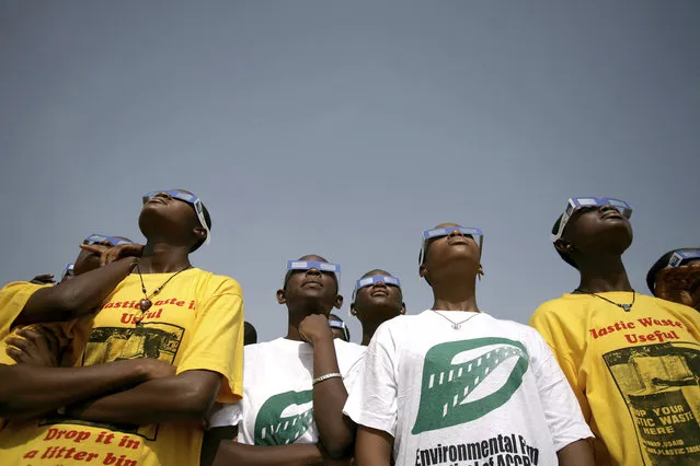 A group of school children look at the solar eclipse in Accra, Ghana, Wednesday, March 29, 2006, which swept from Brazil to Mongolia. (Photo by Olivier Asselin/AP Photo)