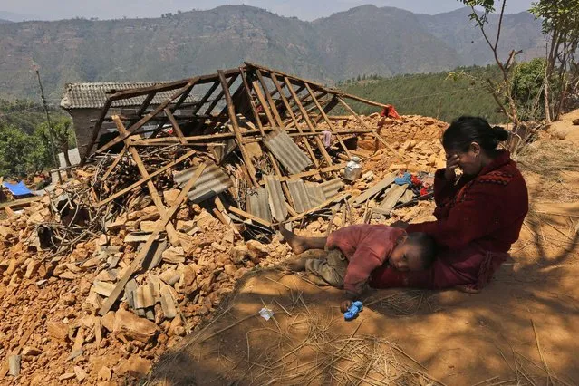A Nepalese woman sits with her son near their house, destroyed in last week's earthquake, in Pauwathok village, Sindhupalchok district, Nepal, Saturday, May 2, 2015. Life has been slowly returning to normal in Kathmandu, but to the east, angry villagers in parts of the Sindhupalchok district said Saturday they were still waiting for aid to reach them. (Photo by Manish Swarup/AP Photo)