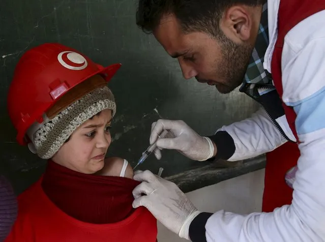 A member of the Syrian Arab Red Crescent administers a vaccination to a girl at a school in the rebel held Douma neighborhood of Damascus, Syria March 21, 2016. (Photo by Bassam Khabieh/Reuters)