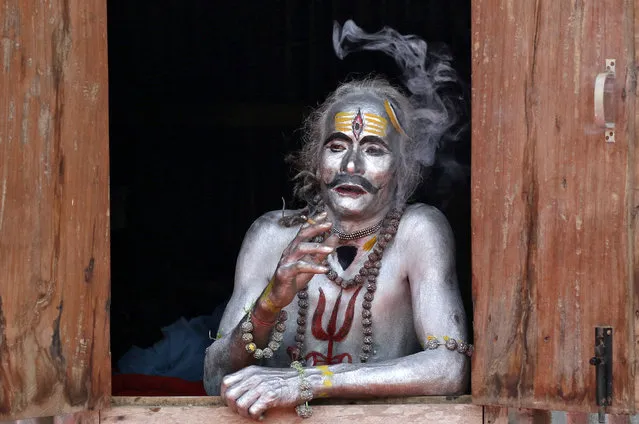 A devotee smokes as he waits to perform during the annual Hindu festival of Gajan on the outskirts of Agartala, India, April 13, 2019. (Photo by Jayanta Dey/Reuters)