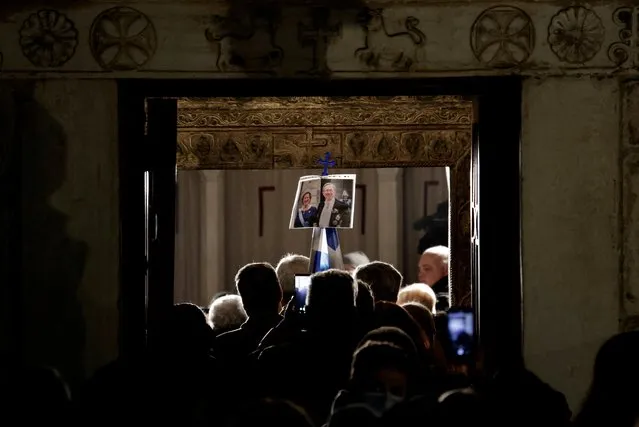 A photo of the late former King of Greece Constantine II and his wife Anne-Marie hangs on a Greek national flag as people line up to pay their respects at Saint Eleftherios chapel, where he lies at rest before the funeral service, in Athens, Greece on January 16, 2023. (Photo by Alkis Konstantinidis/Reuters)