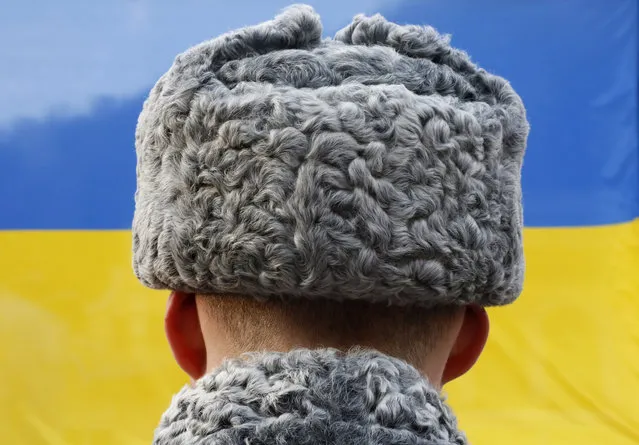 A Russian honor guard soldier looks at the national Ukrainian flag, lifted in honor Vitaly Lukyanenko of Ukraine, winner of the men's biathlon men's 7.5km, visually impaired event during medal ceremony at the 2014 Winter Paralympic, Sunday, March 9, 2014, in Krasnaya Polyana, Russia. (Photo by Dmitry Lovetsky/AP Photo)