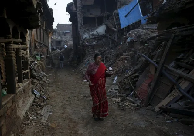 A woman holds prayer items as she walks past collapsed houses, in the early morning hours in  Bhaktapur near Kathmandu, Nepal, May 14, 2015. (Photo by Ahmad Masood/Reuters)