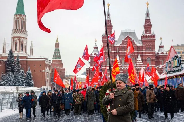 Russian Communist party supporters march to lay flowers to the tomb of late Soviet leader Joseph Stalin during a memorial ceremony to mark the 142nd anniversary of his birth at Red Square in Moscow on December 21, 2021. While historians blame Stalin for the deaths of millions in purges, prison camps and forced collectivization, many in Russia still praise him for leading the Soviet Union to victory over Nazi Germany in World War II. (Photo by Dimitar Dilkoff/AFP Photo)