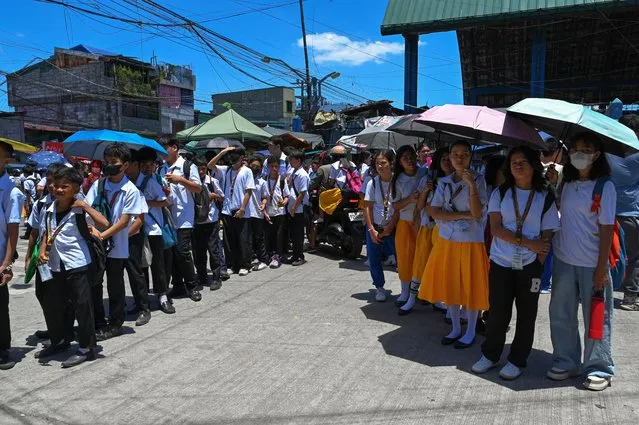 Students use umbrellas to protect themselves from the sun as they line up to wait for their classes outside their school in Manila on April 2, 2024. More than a hundred schools in the Philippine capital shut their classrooms on April 2, as the tropical heat hit “danger” levels, education officials said. (Photo by Jam Sta Rosa/AFP Photo)