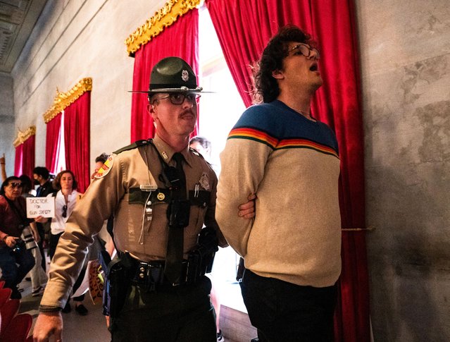 Tennessee State Troopers detain a gun reform activist after the Republican Speaker of The House ordered the House gallery cleared following a vote by the House to adopt Senate Bill 1325 at the Tennessee State Capitol building in Nashville, Tennessee, April 23, 2024. The bill will authorize teachers, principals, and school personnel to carry a concealed handgun on school grounds. The protester was given a citation and later released. (Photo by Seth Herald/Reuters)