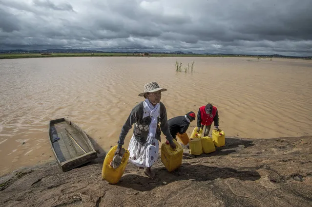Residents cross flooded land and canal in Madagascar's capital Antananarivo, on Friday, March 10, 2017, to collect fresh water. Cyclone Enawo hit land Tuesday, claiming the lives of at least five people and forcing some 10,000 people abandon their homes because of storm damage. (Photo by Alexander Joe/AP Photo)