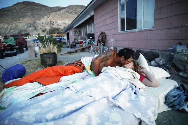 Chimene Jackson kisses her husband Johnnie shortly after dawn outside her parents' home, which has been deemed uninhabitable due to structural damage from the recent 7.1 magnitude earthquake, on July 8, 2019 in Trona, California. Homeowners Benny and Anna Sue Eldridge, husband and wife, are currently sleeping outside the home with other family members on mattresses and in trucks for safety. Firefighters told them a stronger earthquake could cause the house to collapse. Anna Sue's father constructed the home with Benny's help in 1961. During the daytime they have been packing furniture, heirlooms and other items to place into storage as they try to decide where they will live next or if they will rebuild. (Photo by Mario Tama/Getty Images)