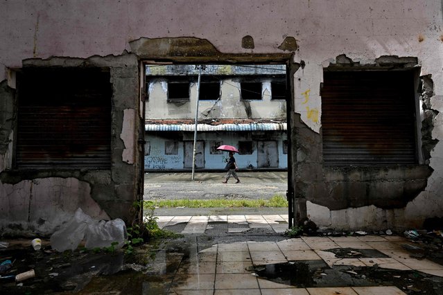 A man is seen past a derelict building in the Chinatown district of Honiara, the Solomon Islands capital, on April 16, 2024. Merchants in Solomon Islands' gritty Chinatown were on April 16 preparing for the prospect of post-election violence, fearful the district will again be targeted if the Pacific nation reelects a pro-Beijing leader. Unruly mobs tore through the shopping district during riots in 2019 and 2021, their anger fuelled in part by China's growing sway over the government. (Photo by Saeed Khan/AFP Photo)