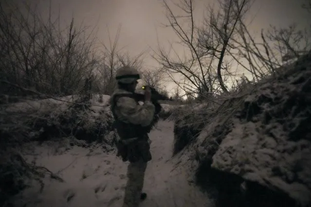 A Ukrainian serviceman adjusts a night vision device attached to his weapon while patrolling positions on a frontline outside Avdiivka, Donetsk region, eastern Ukraine, Friday, February 4, 2022. (Photo by Vadim Ghirda/AP Photo)