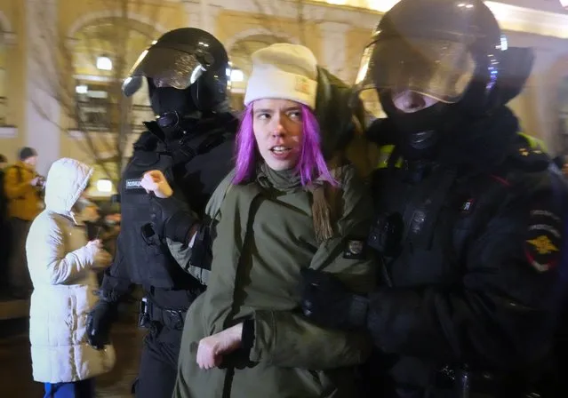 Police officers detain a woman in St. Petersburg, Russia, Friday, February 25, 2022. Shocked Russians turned out by the thousands Thursday to decry their country's invasion of Ukraine as emotional calls for protests grew on social media. Some 1,745 people in 54 Russian cities were detained, at least 957 of them in Moscow. (Photo by Dmitri Lovetsky/AP Photo)
