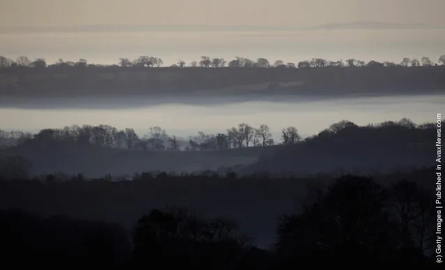 Mist and fog covers fields as the sun rises over the Somerset Levels in Glastonbury, England