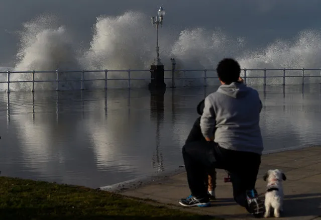 A man takes pictures as waves crash against the seafront of San Lorenzo beach in Gijon, northern Spain, February 28, 2017. (Photo by Eloy Alonso/Reuters)