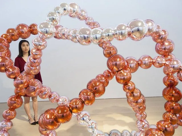 A woman looks at a sculpture entitled “Noeud rose miroir” by French artist Jean-Michel Othoniel are on display in the solo exhibition “Monumental Sculptures” at the Galerie Perrotin in Hong Kong, China, 13 May 2014. The exhibit runs until 21 June. (Photo by Alex Hofford/EPA)