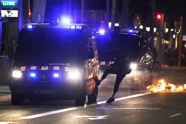 A protestor kicks a police van during clashes in Barcelona, Spain, Thursday, October 17, 2019. Catalonia's separatist leader vowed Thursday to hold a new vote to secede from Spain in less than two years as the embattled northeastern region grapples with a wave of violence that has tarnished a movement proud of its peaceful activism. (Photo by Emilio Morenatti/AP Photo)
